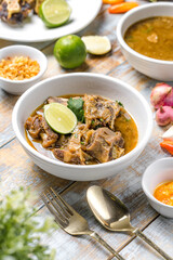 Oxtail soup served warm with sliced lime.