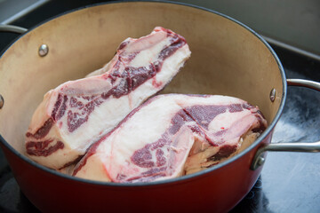 Defrosting two short-ribs meat slices in a red pot