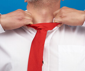 man in a white office shirt tears off a red satin tie from his neck