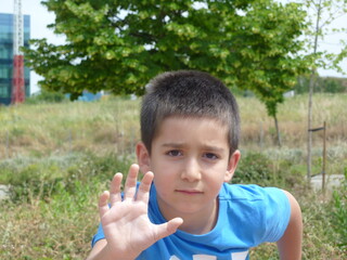 Fototapeta premium Kid in a park greeting with his right hand