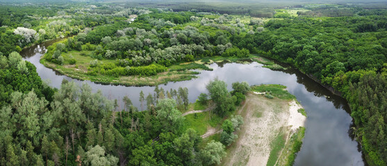 Aerial panorama with river zigzag through green forest. Rural landscape with river beach and ground...
