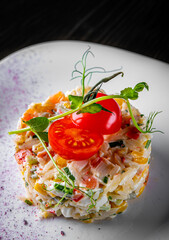 Salad with crab sticks, corn, rice, tomato and eggs in white plate