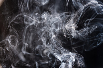 White abstract shaped smoke against black background.