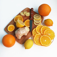 Naklejka na ściany i meble Sliced fruits isolated on cutting board. Lemon, orange and ginger slices on wooden board. Healthy food isolated on white background.