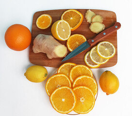 Sliced fruits isolated on cutting board. Lemon, orange and ginger slices on wooden board. Healthy food isolated on white background.