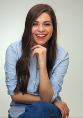 Young woman dressed blue denim shirt sitting on stool.