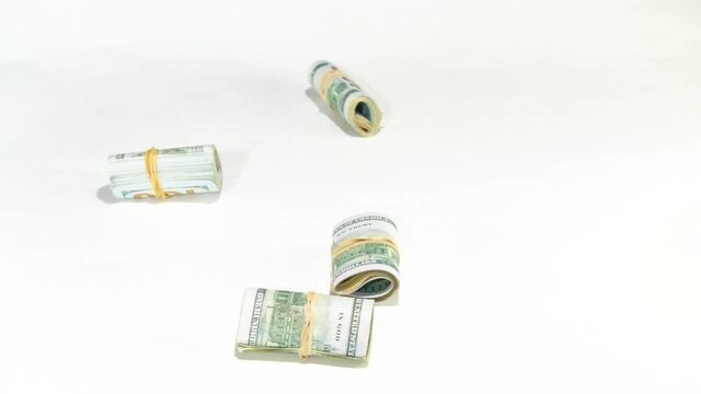 433 Hundred dollar bills wrapped in rubber bands in circles falling from the sky onto a white background