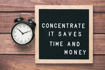 Inspirational motivational business quote Concentrate. It Saves Time and Money words on a letter board on wooden background near vintage alarm clock. Success and motivation concept.