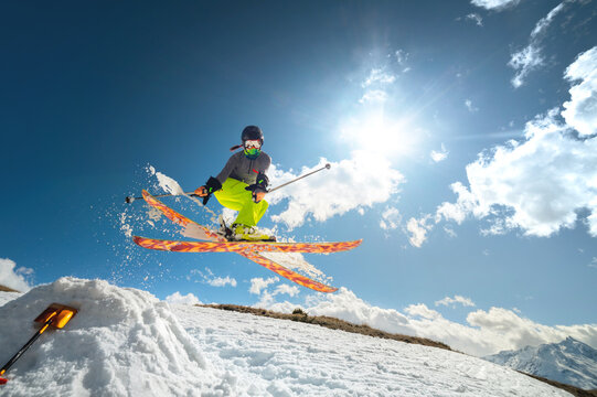 Girl skier in flight after jumping from a kicker in the spring against sun and blue sky. Close-up wide angle. © yanik88