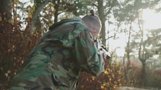 The versatile view of soldier tracks the object with a rifle sight at forest