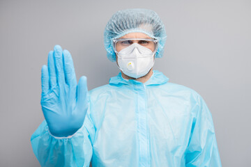 Photo of guy expert doc virologist hold palm stop patients stepping into danger infected zone wear gloves mask hazmat blue uniform surgical cap goggles isolated grey color background