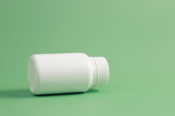 White plastic medicine bottle on green background