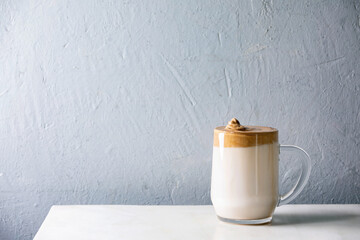 Dalgona frothy coffee trend korean drink milk latte with coffee foam in glass mug on white marble...