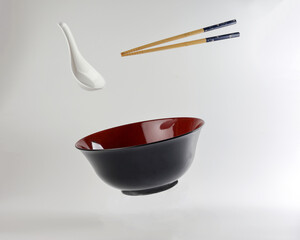 Empty oriental Japanese Chinese soup bowl spoon chopstick elevated flying in air red black white