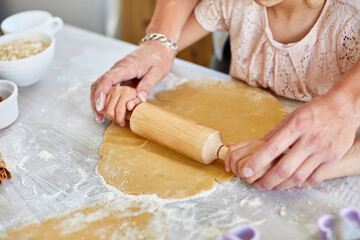 Father showing his little daughter how to roll dough for cookies, baking in kitchen, family cooking at home..