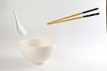 Empty oriental Japanese Chinese soup bowl spoon chopstick elevated flying in air off white