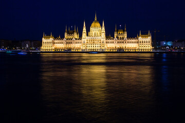 Naklejka premium Illuminated Budapest parliament building at night with dark sky and reflection in Danube river