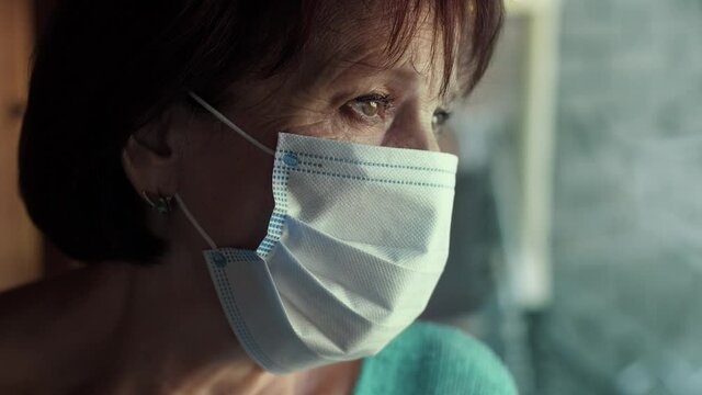 Elderly Woman In Face Mask Behind Window