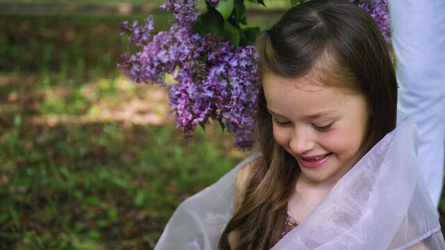 girl model is photographed on a background of purple flowers of lilac