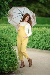 Young pregnant woman under umbrella in summer forest.