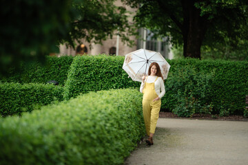 Young pregnant woman under umbrella in summer forest.