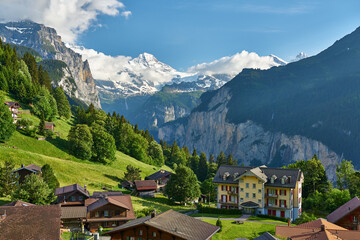 Fototapeta na wymiar Lauterbrunnen Valley at sunset with snowy mountains, waterfall and green nature. Landscape panorama taken from mountain village Wengen, Switzerland