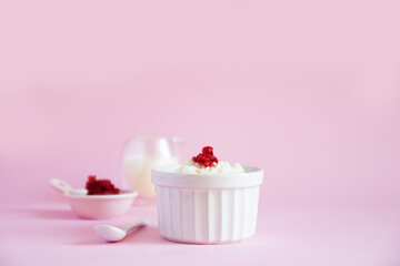 Milk rice porridge with frozen berries on a pink background