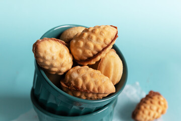 Delicious homemade walnut cookies in a bowl on a blue background with a copy space