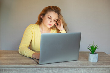 Tired woman with a laptop .Problem with a laptop. Girl with a laptop sits at the  table