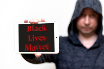 Portrait of a hooded white man holds tablet with the inscription Black Lives Matter. protests of...