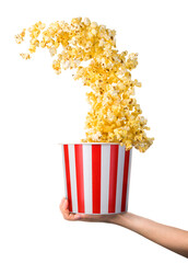 Woman hand holding striped bucket with flying popcorn isolated on white