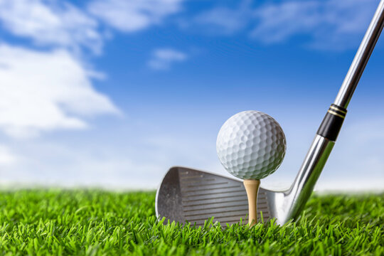 Golf club and golf ball on tee onto the green grass ready to be shot.