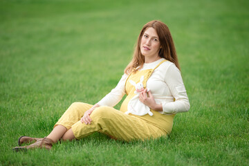 Expecting young female mother posing in park holding plush toy