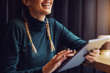 Closeup of girl sitting in cafeteria and surfing on internet over tablet.