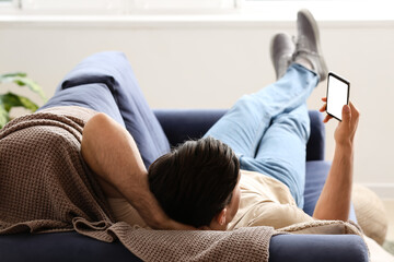 Lazy man with mobile phone spending day off at home