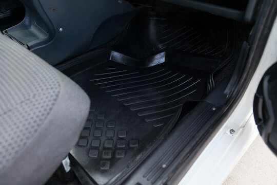 Close-up of a clean black rubber auto mat under a passenger seat in an old Russian car after dry cleaning.