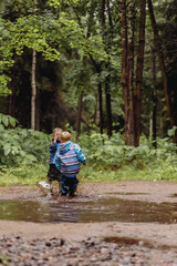 little boys brothers jumping in a muddy puddle. Image with selective focus and toning