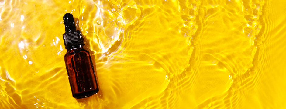 Essential oil in water on a yellow background. The concept of aromatherapy. The preservation of the health, natural cures. Aromatherapy and perfumes concept