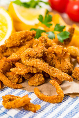 Crispy Breaded Clam Strips Snack Size. Deep Fried Breaded Clams Fingers and French Fried Potatoes with Tartar Dipping Sauce on a wooden board. Selective focus.