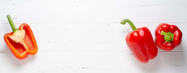 Three red ripe bell peppers. White wooden background. Copy space