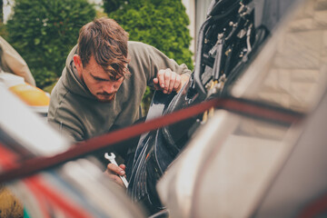 A young caucasian male wrenching an outboard engine as a part of a service maintenance operation on an engine. Workshop for outboard engines.