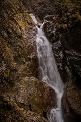 Fast flowing water over small rapids and waterfalls in Vintgar gorge, close to Borovnica, slovenia, on a dull winter day.