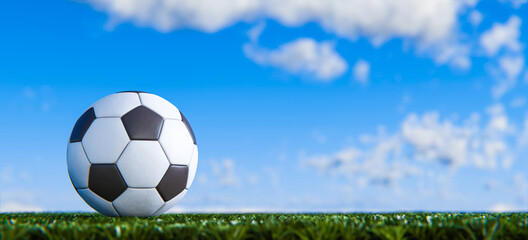 Fußball auf grünem Rasen vor Himmel