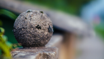 Fototapeta na wymiar Old weathered rough cement or concrete ball used as a decoration on the top of a wall or fence next to a residential building.
