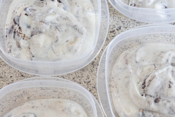 Homemade cookies and cream yogurt put into individual containers on a domestic kitchen counter.