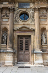 Antique inlaid wooden door with carved stone structure in an ancient palace in Paris.