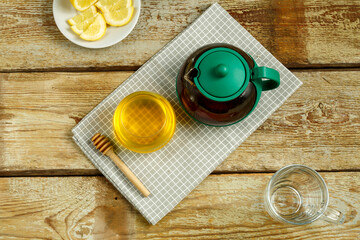 Kettle with brewed tea and honey with lemon on the table.