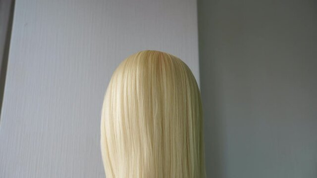 Beautiful wig with straight white hair is standing in a beauty salon. 4K slow motion footage