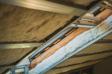 Reconstruction of a roof in a house. Cut away side view of layer of a roof on a house. Wooden trestles, wool insulation and drywall profiles in a house.