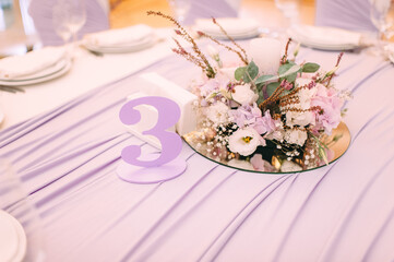 Banquet, restaurant. Table setting with tablecloth. White plates, cutlery, glasses, napkin, floral arrangements, food, chairs, flowers